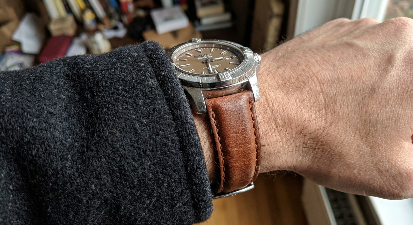 Close-up of a padded calfskin leather strap on a Breitling Avenger resting against the cuff of a heavy wool winter coat