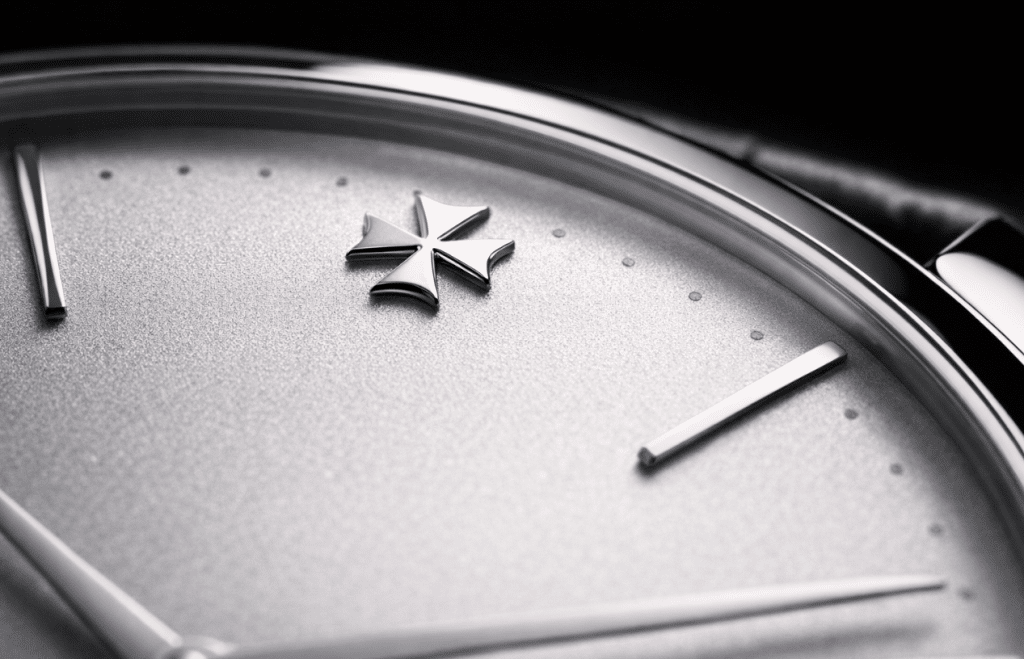 [IMAGE: Close-up of an MKS Patrimony dial showing the 12 o'clock Maltese cross and the curved opaline surface]