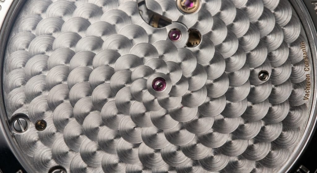 The circular graining or perlage on the mainplate of an APSF Calibre 5100 movement shows perfectly aligned 50% overlap ratios under 20x magnification.
