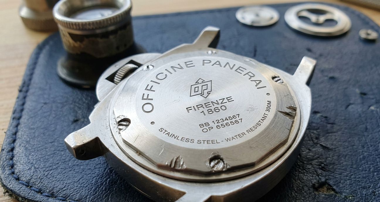 Close-up of a replica watch caseback with visible pry marks and stripped screw heads.