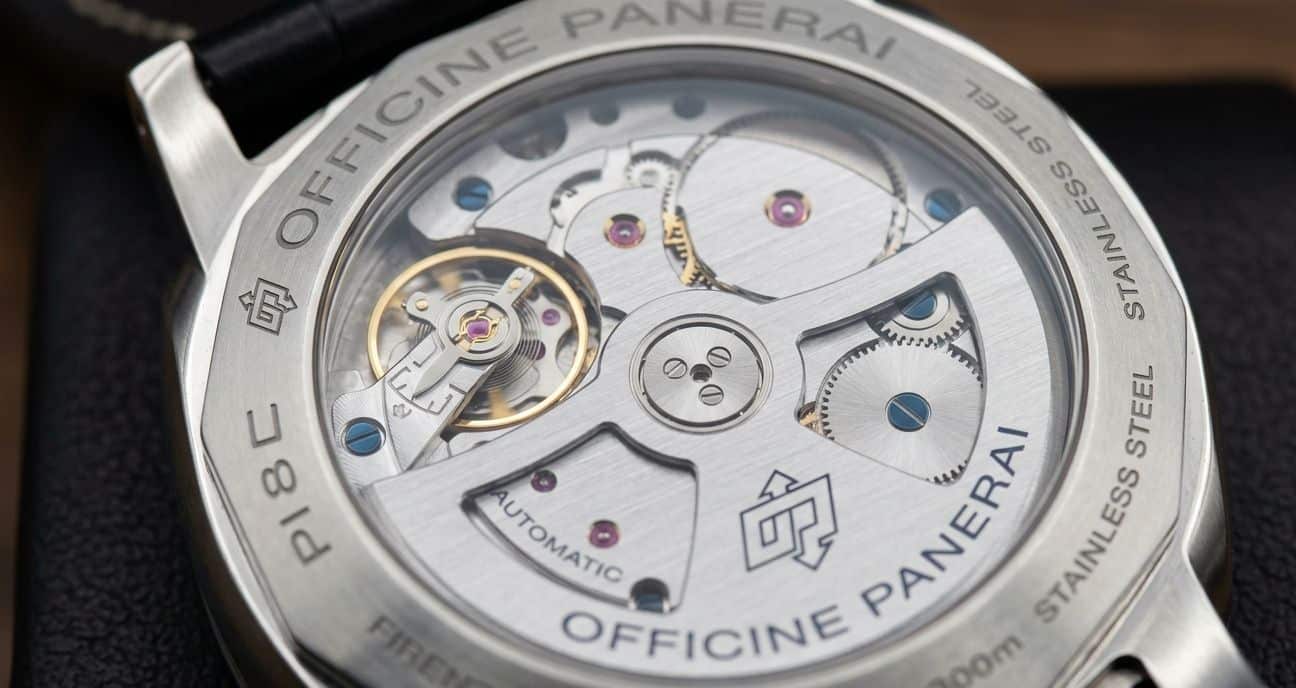 Close-up of a replica Panerai movement through a display caseback, showing intricate gears and balance wheel