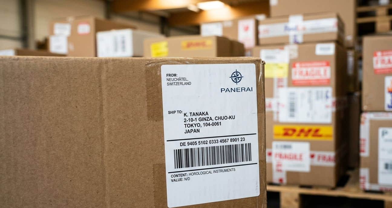 A shipping label being printed, with a blurred background of international shipping boxes.