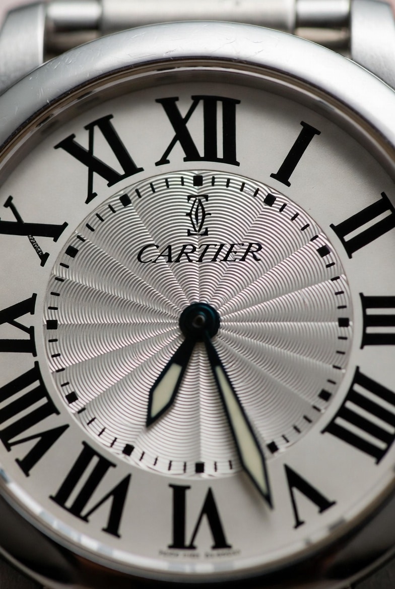 A close-up of a Cartier replica dial highlighting potential flaws in Roman numeral printing and hand finish.