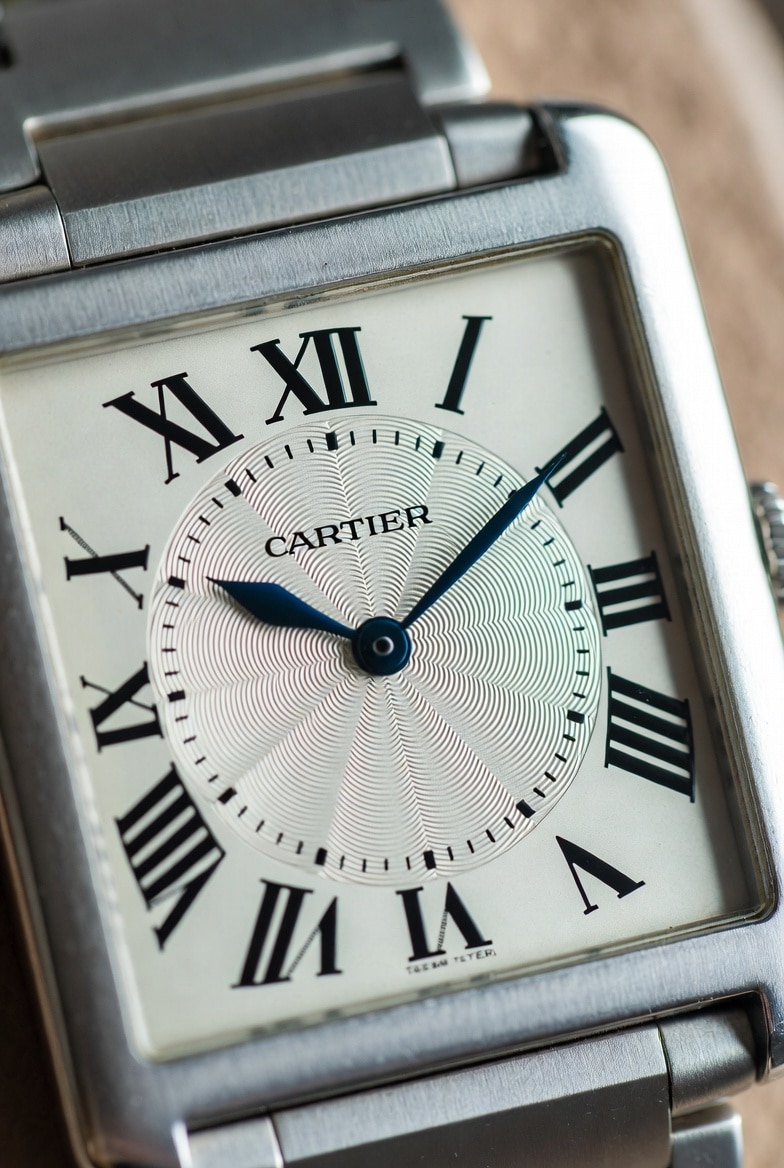 A close-up of a Cartier Tank super clone's dial, showing crisp Roman numerals and blued hands.