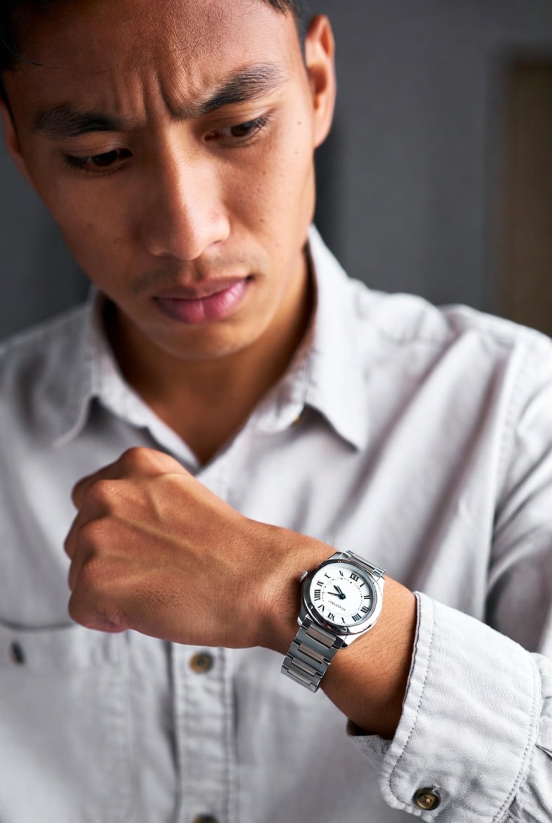 A person looking at a watch on their wrist with a conflicted expression, reflecting the social dilemma of a replica gift.