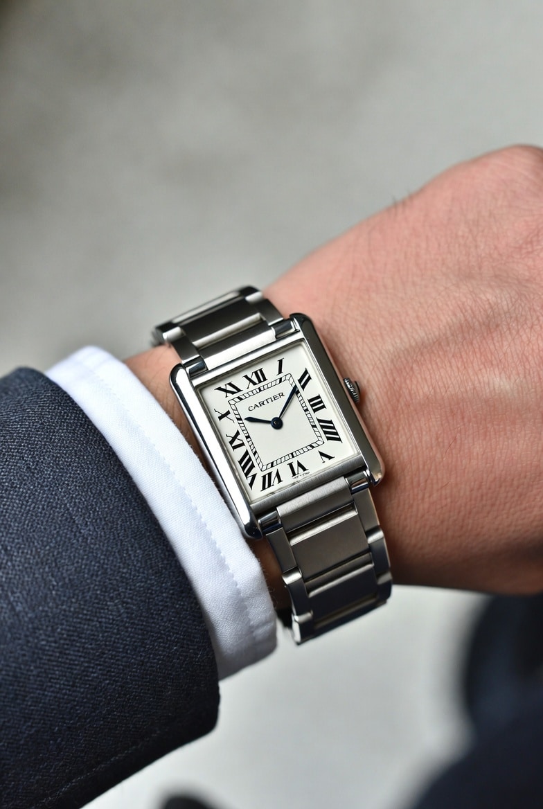 A close-up shot of a Cartier Tank replica on a wrist, highlighting its profile and how it sits under a shirt cuff.