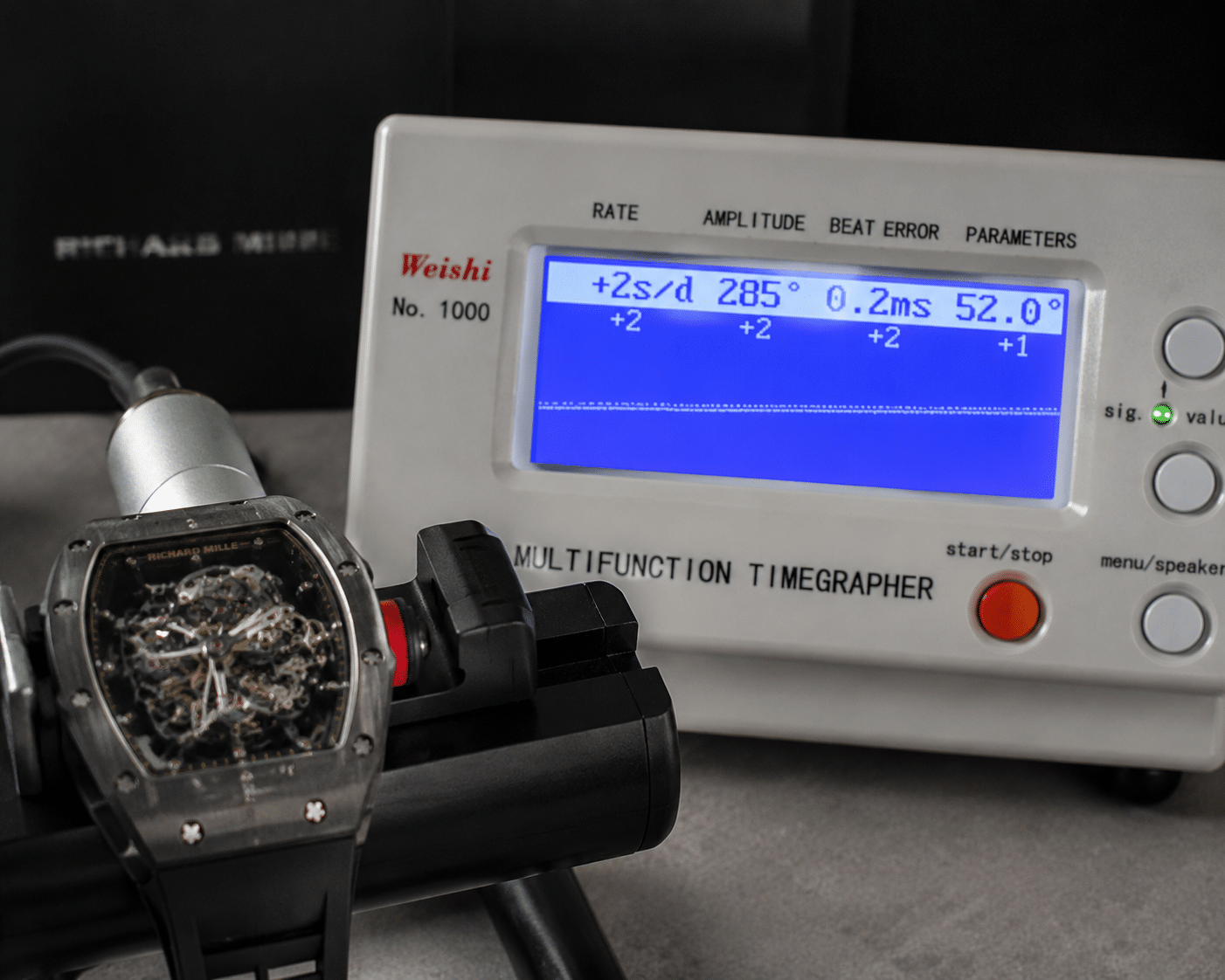 close-up of a replica RM movement running on a timegrapher machine, showing the rate, amplitude, and beat error readings on the display screen