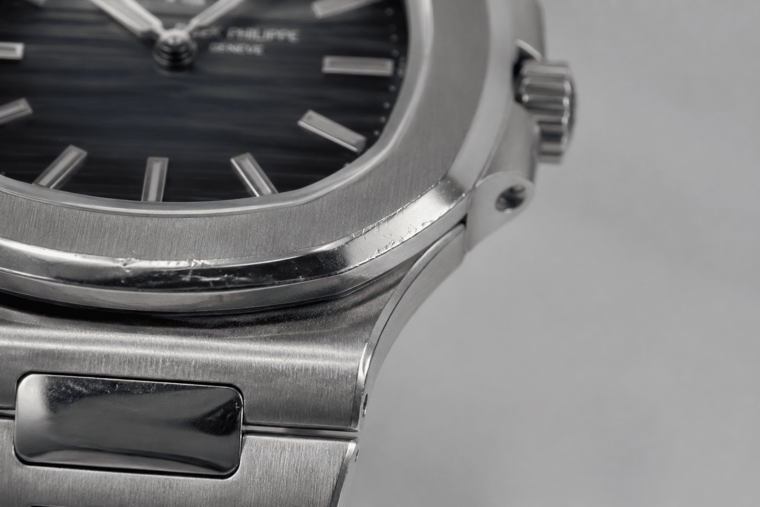 close-up of a worn Patek Philippe super clone case showing brushed finishing, polished edge scratches, and bezel wear under neutral lighting